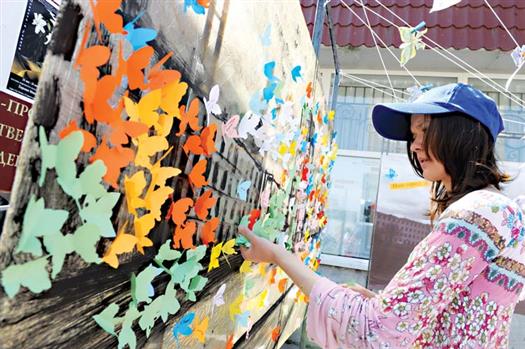 Участники праздника закрасили цветными бабочками фотографию с серыми, унылыми городскими застройками