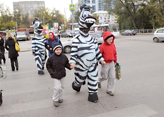 Молодые люди в экстравагантных костюмах помогали пешеходам переходить через дорогу.